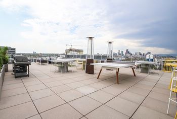 A rooftop patio with a table and chairs overlooking a city skyline.